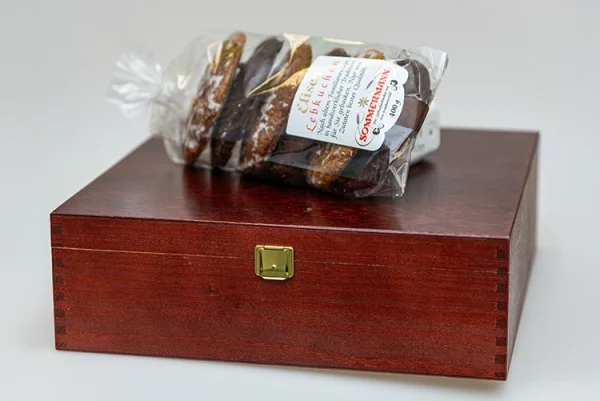 Eine Packung Lebkuchen mit Schokoguss und Zuckerglasur liegt auf der Holztruhe